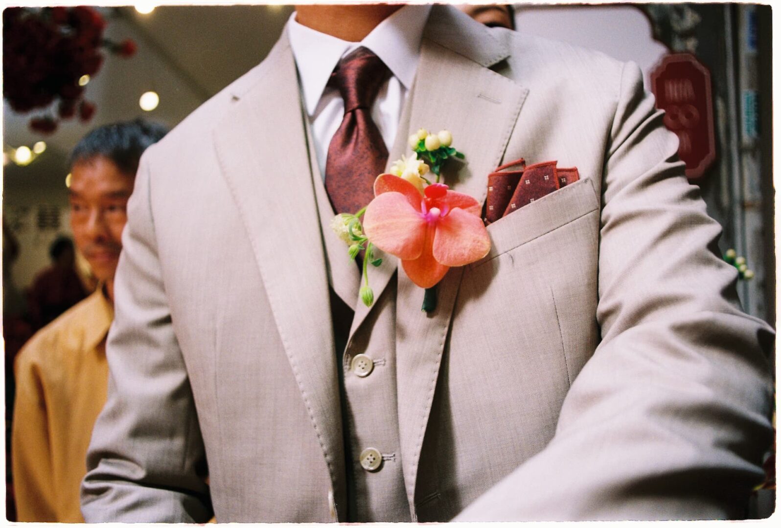 Close-up of a groom wearing a light-colored suit with a floral boutonniere and pocket square on his wedding day